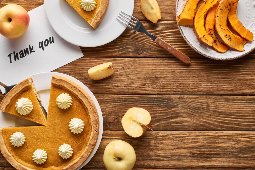 вид сверху на вкусный тыквенный пирог, яблоки и благодарственная открытка на деревянном деревенском столе
 - Фото, изображение