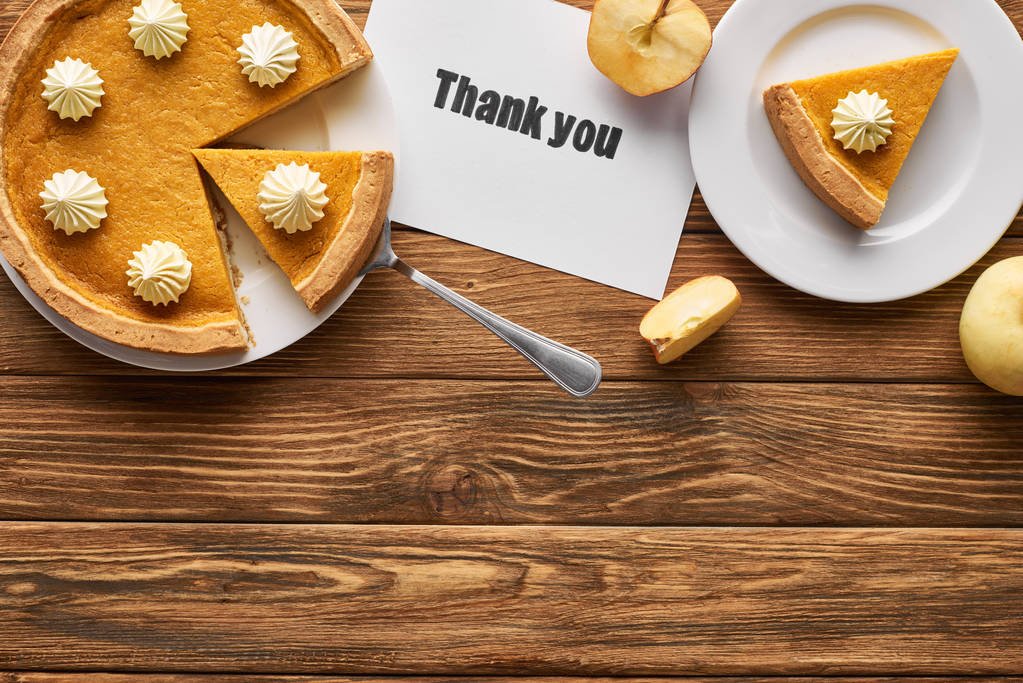 вид сверху на вкусный тыквенный пирог, яблоки и благодарственная открытка на деревянном деревенском столе
 - Фото, изображение
