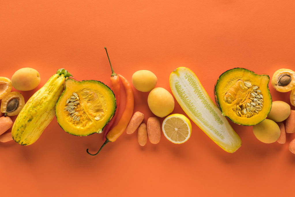 felső nézet a sárga gyümölcsök és zöldségek narancssárga alapon - Fotó, kép