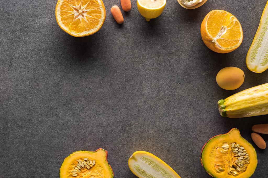 Draufsicht auf gelbes Obst und Gemüse auf grauem, strukturiertem Hintergrund mit Kopierfläche - Foto, Bild