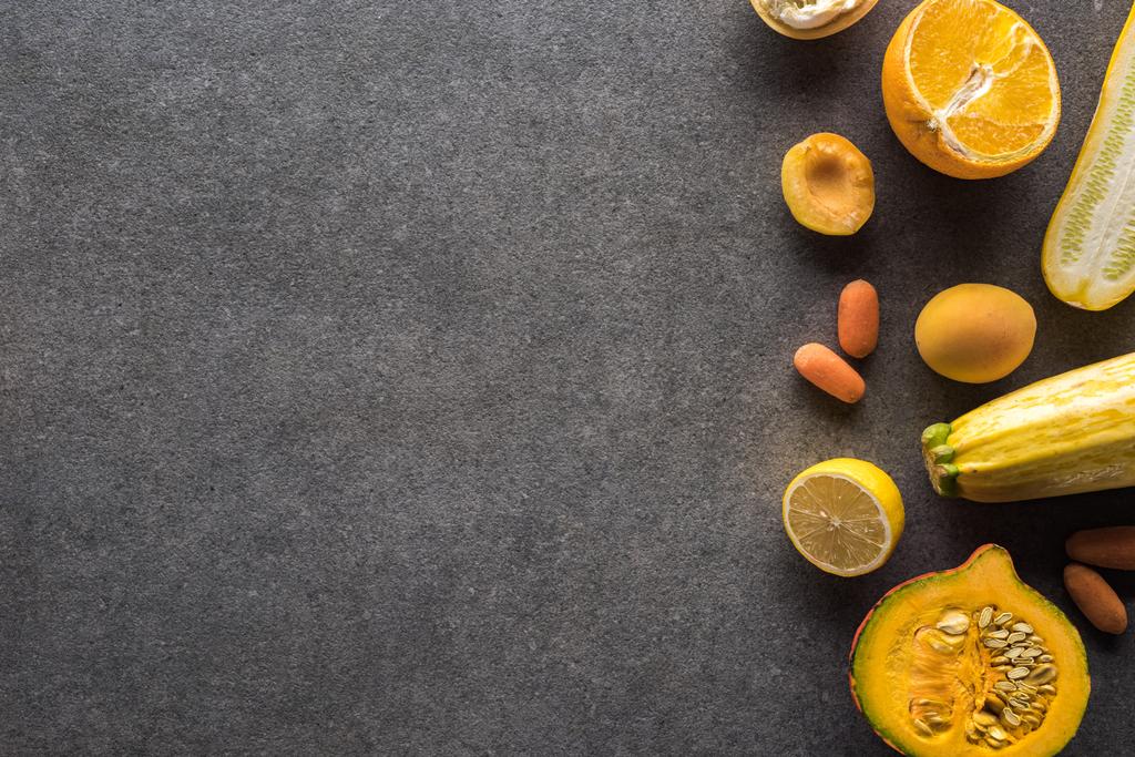 ylhäältä näkymä keltaisia hedelmiä ja vihanneksia harmaa kuvioitu tausta kopioi tilaa
 - Valokuva, kuva