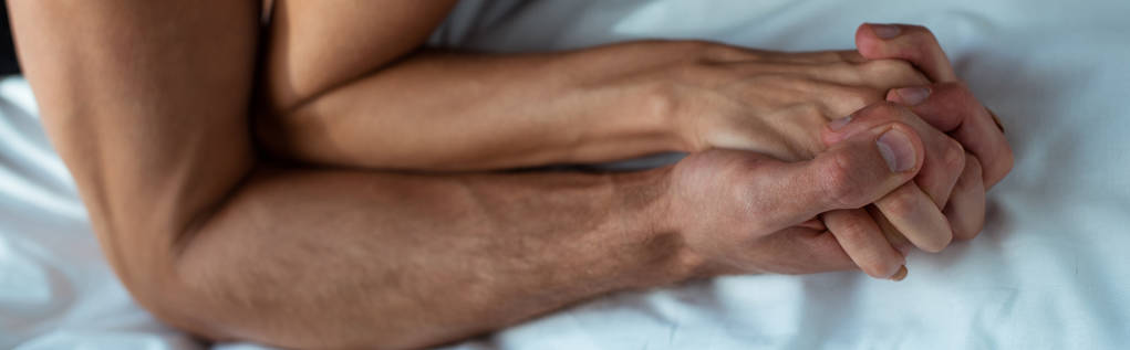 πανοραμική λήψη του παθιασμένου άνδρα και της γυναίκας κρατώντας τα χέρια στην κρεβατοκάμαρα  - Φωτογραφία, εικόνα