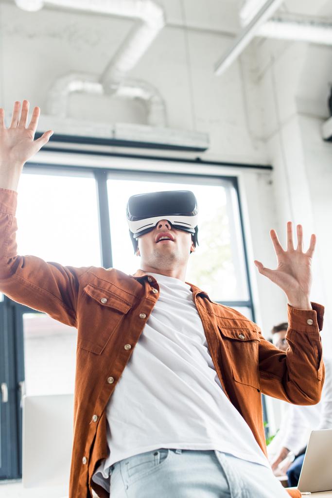 young businessman gesturing while using vr headset in office - Photo, Image