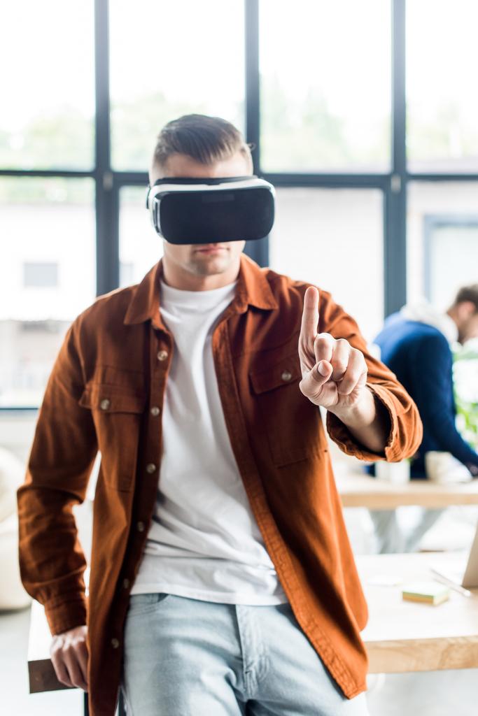 jonge zakenman aanraken iets met de vinger tijdens het gebruik van virtual reality headset in het kantoor - Foto, afbeelding