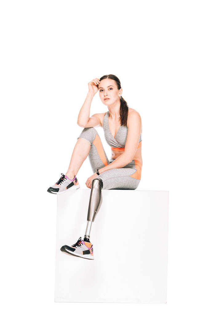 zdravotně postižená sportovkyně s protézou nohy sedí izolované na bílém - Fotografie, Obrázek