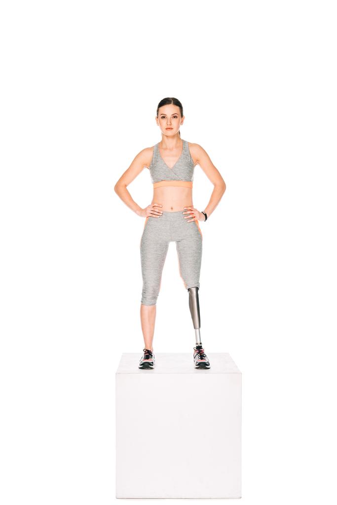 volledige weergave van gehandicapte sportvrouw met prothese been staande met handen op heupen geïsoleerd op wit - Foto, afbeelding