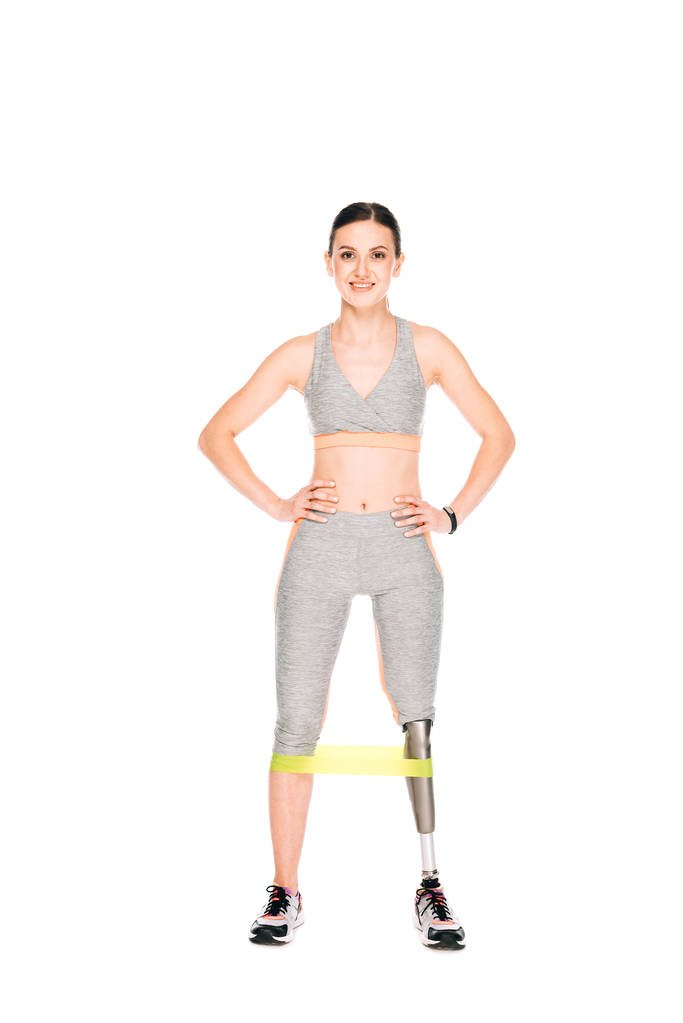 full length view of smiling disabled sportswoman with resistance band isolated on white - Photo, Image