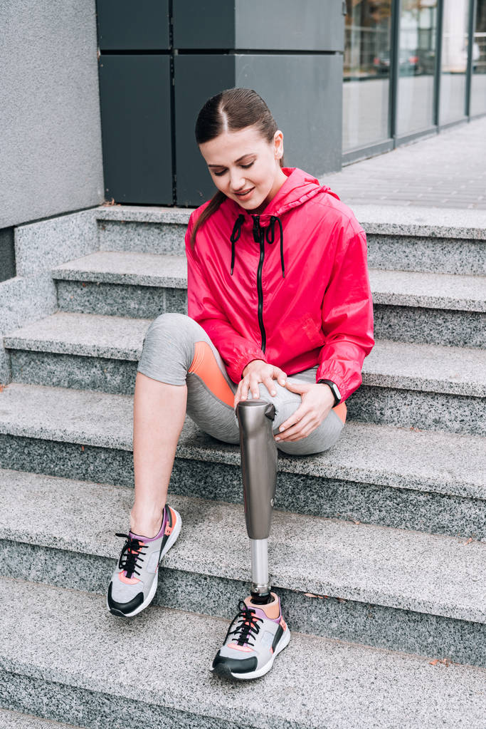 mozgássérült sportnő protézissel ül a lépcsőn az utcán - Fotó, kép