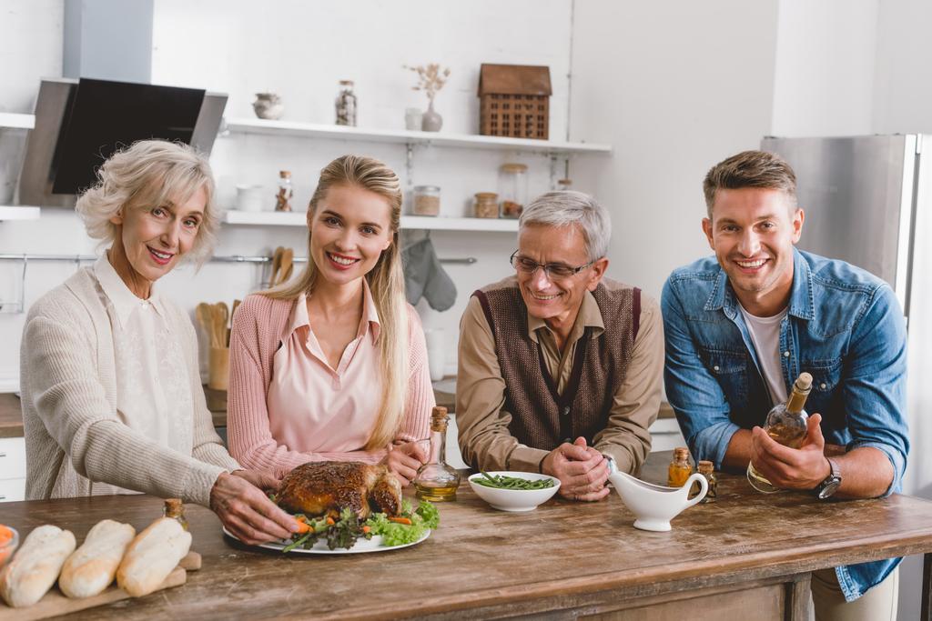 smiling family members holding plate with turkey and looking at camera in Thanksgiving day   - Photo, Image