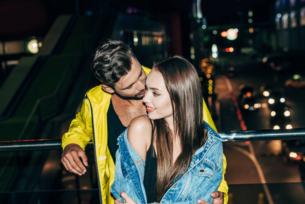 gece şehirde çekici ve gülümseyen kız arkadaşı öpüşme erkek arkadaşı yüksek açı görünümü  - Fotoğraf, Görsel