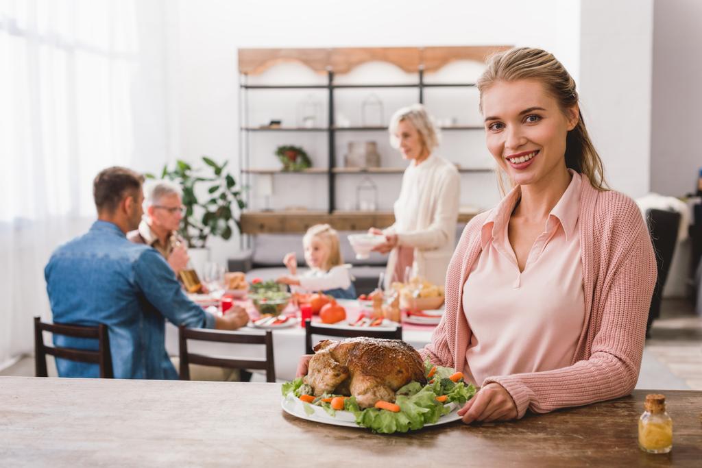 smiling mother holding plate with tasty turkey in Thanksgiving day    - Photo, Image