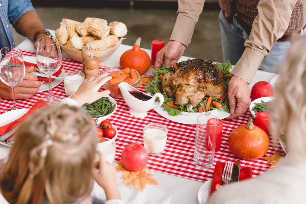 vista ritagliata del nonno mettere sul piatto del tavolo con tacchino nel giorno del Ringraziamento
       - Foto, immagini