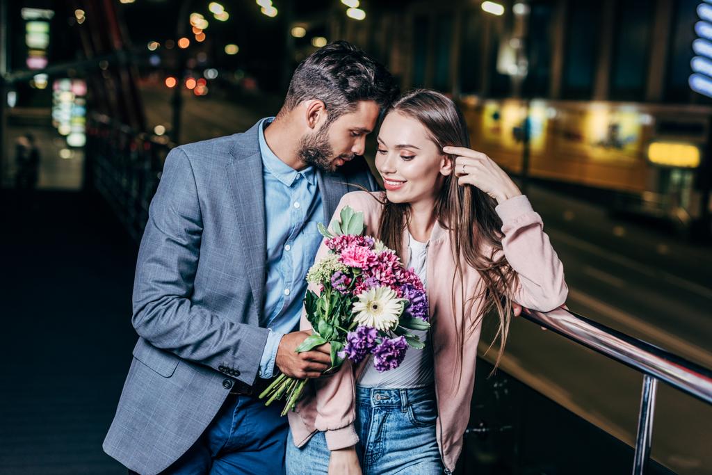 夜の街で花束を与え、魅力的な女性にキスをするハンサムなビジネスマン  - 写真・画像