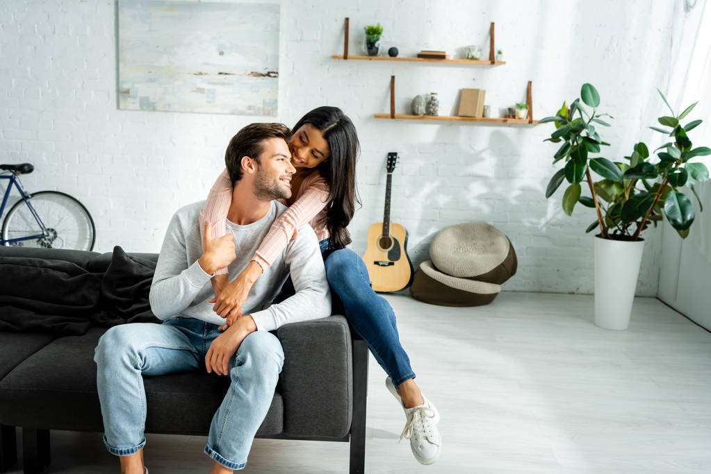 african american woman and handsome man smiling and hugging in apartment  - Photo, Image