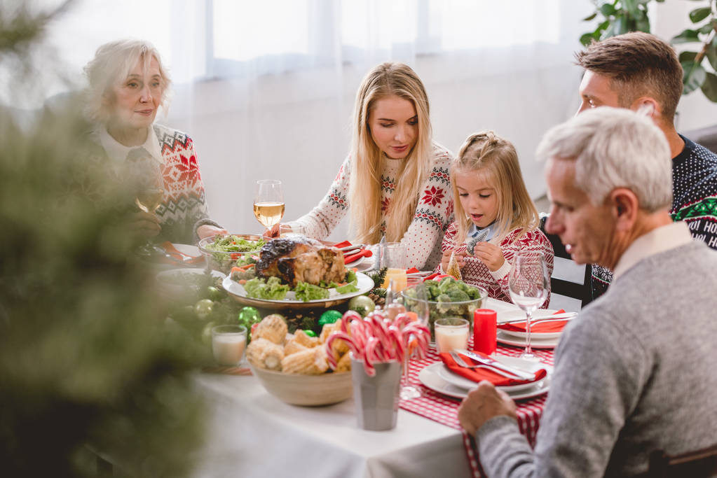 επιλεκτική εστίαση των μελών της οικογένειας που κάθονται στο τραπέζι και γιορτάζουν τα Χριστούγεννα  - Φωτογραφία, εικόνα