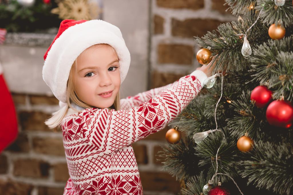 aranyos gyerek télapó kalap és pulóver díszítő karácsonyfa - Fotó, kép
