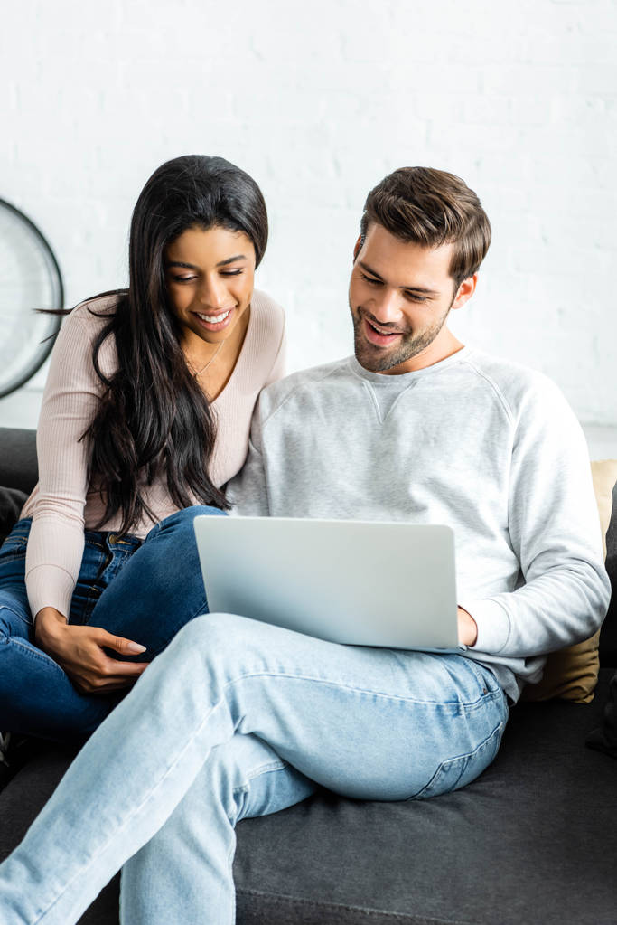smiling african american woman and handsome man looking at laptop  - Photo, Image