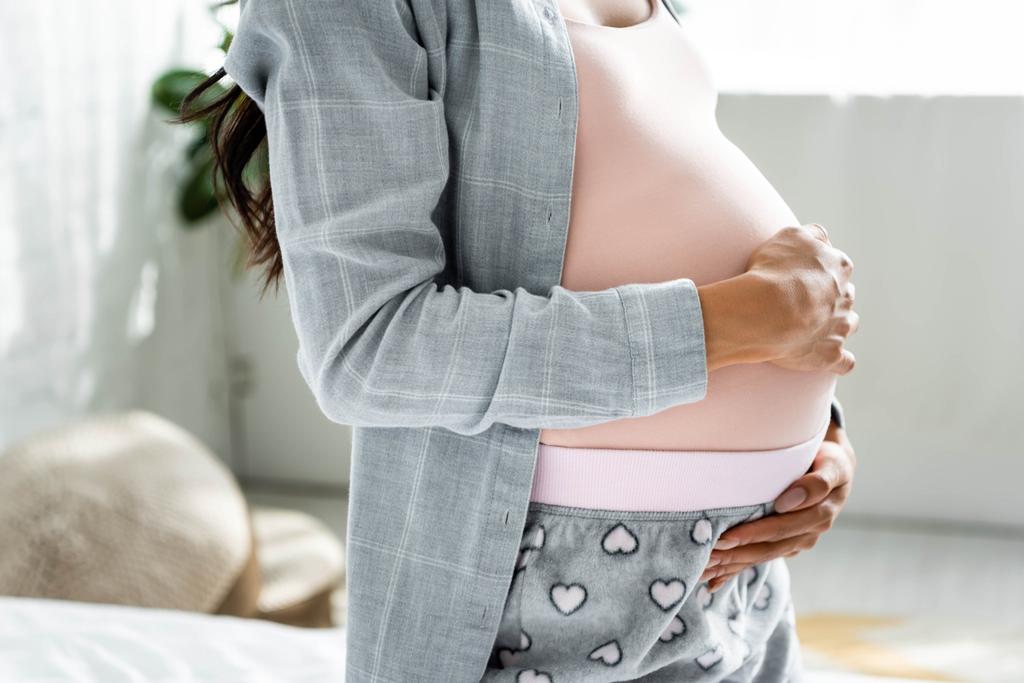 vista recortada de mujer embarazada afroamericana en pijama abrazando el vientre
  - Foto, imagen