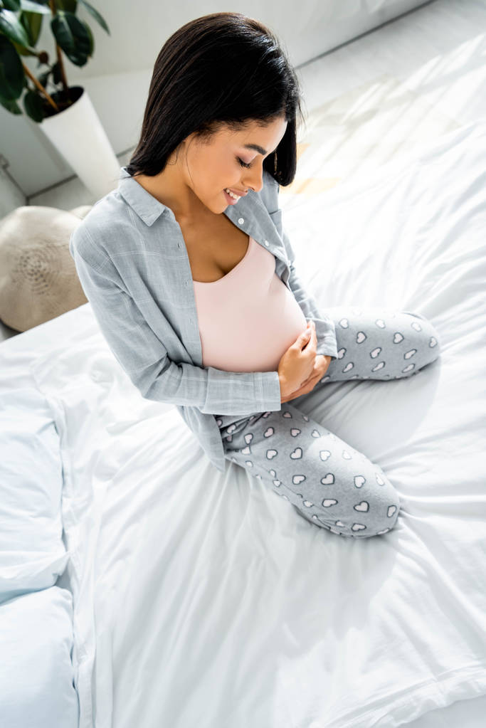 korkea kulma näkymä afrikkalainen amerikkalainen raskaana pyjama hymyilevä ja halaava vatsa
  - Valokuva, kuva