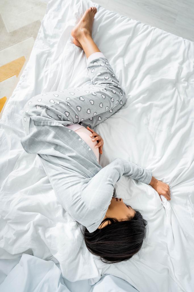 felülnézet az afroamerikai terhes nő pizsama megható a has és az érzés fájdalmat  - Fotó, kép