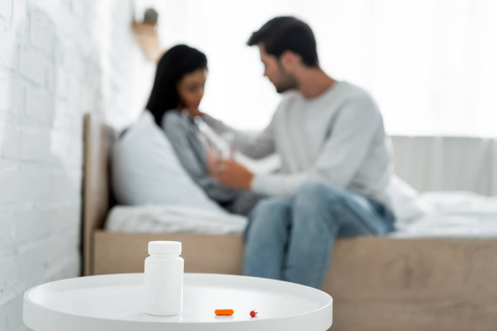 selectieve focus van pillen en fles op witte tafel  - Foto, afbeelding