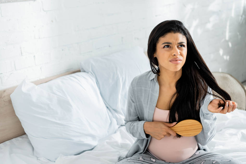 arrabbiato americano donna incinta in pigiama tenendo spazzola per capelli in appartamento
  - Foto, immagini