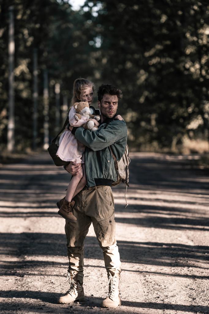 красивый и грязный мужчина, держащий в руках ребенка в Чернобыле, постапокалиптическая концепция
 - Фото, изображение