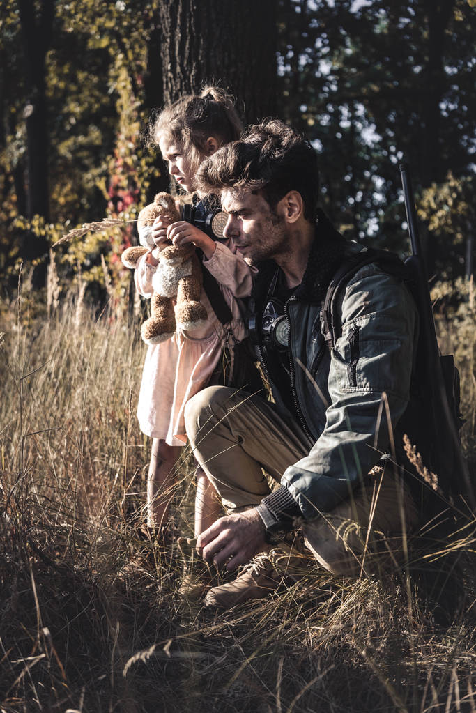 селективная направленность человека и ребенка с противогазами в поле, постапокалиптическая концепция
 - Фото, изображение
