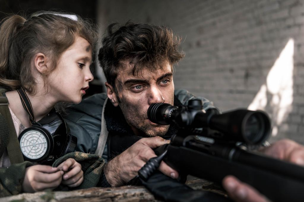 szelektív fókusz a gyerek néz férfi fegyverrel, poszt apokaliptikus koncepció - Fotó, kép