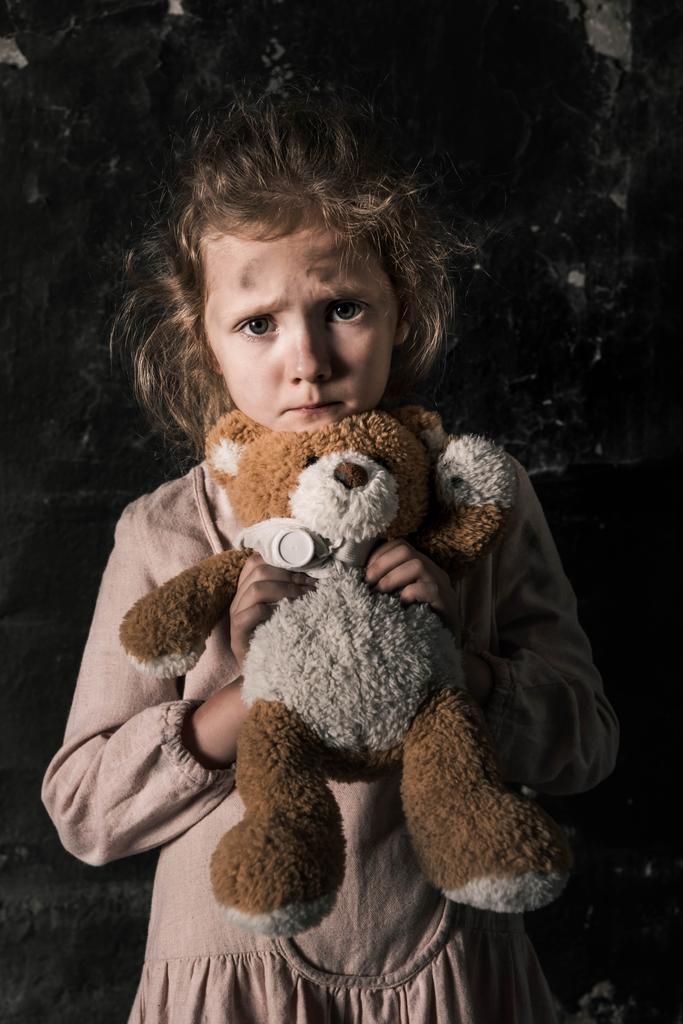 απογοητευμένο παιδί κρατώντας αρκουδάκι στο βρώμικο δωμάτιο, μετα-αποκαλυπτική έννοια - Φωτογραφία, εικόνα