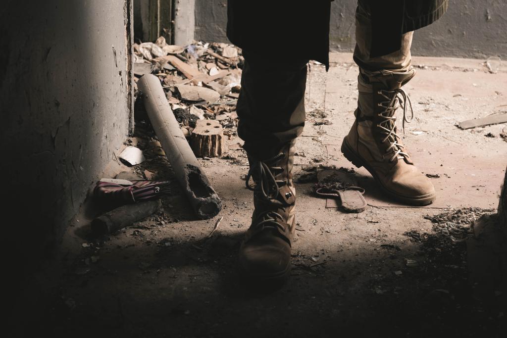 visão cortada do homem de botas em pé na sala intemperizada, conceito pós-apocalíptico
 - Foto, Imagem