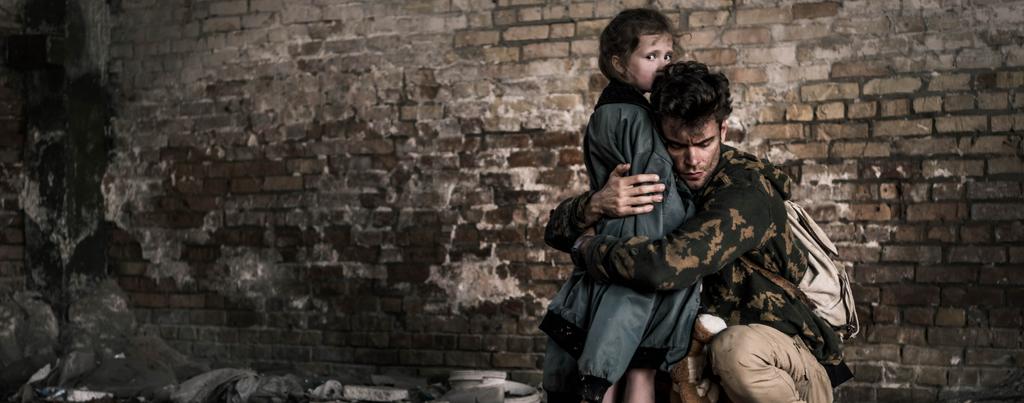 tiro panorâmico de homem bonito abraçando criança perto da parede de tijolo, conceito pós-apocalíptico
 - Foto, Imagem