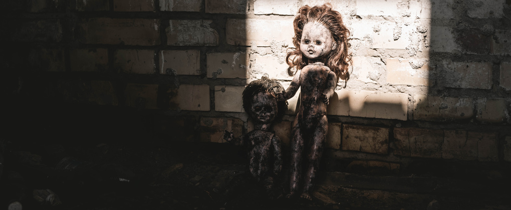 レンガの壁に近い古い怖い赤ん坊の人形のパノラマ写真黙示録的な概念を投稿します - 写真・画像