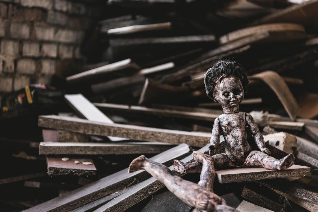Verbrannte und beängstigende Babypuppe in der Nähe beschädigtes Spielzeug und Holzbretter, postapokalyptisches Konzept - Foto, Bild
