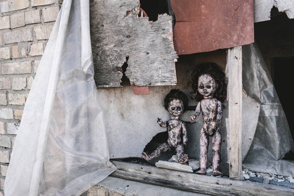 eng en verbrand baby poppen in de buurt van roestig venster, post apocalyptische concept - Foto, afbeelding