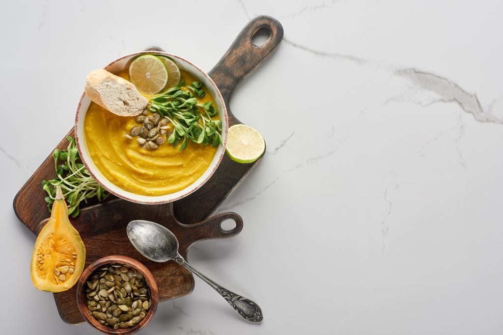 top view of autumnal mashed pumpkin soup on wooden cutting board on marble surface with silver spoon - Photo, Image
