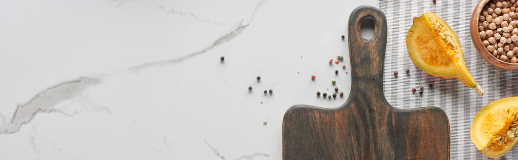 plano panorámico de tabla de cortar de madera con calabaza, garbanzo y pimienta en la superficie de mármol
 - Foto, imagen