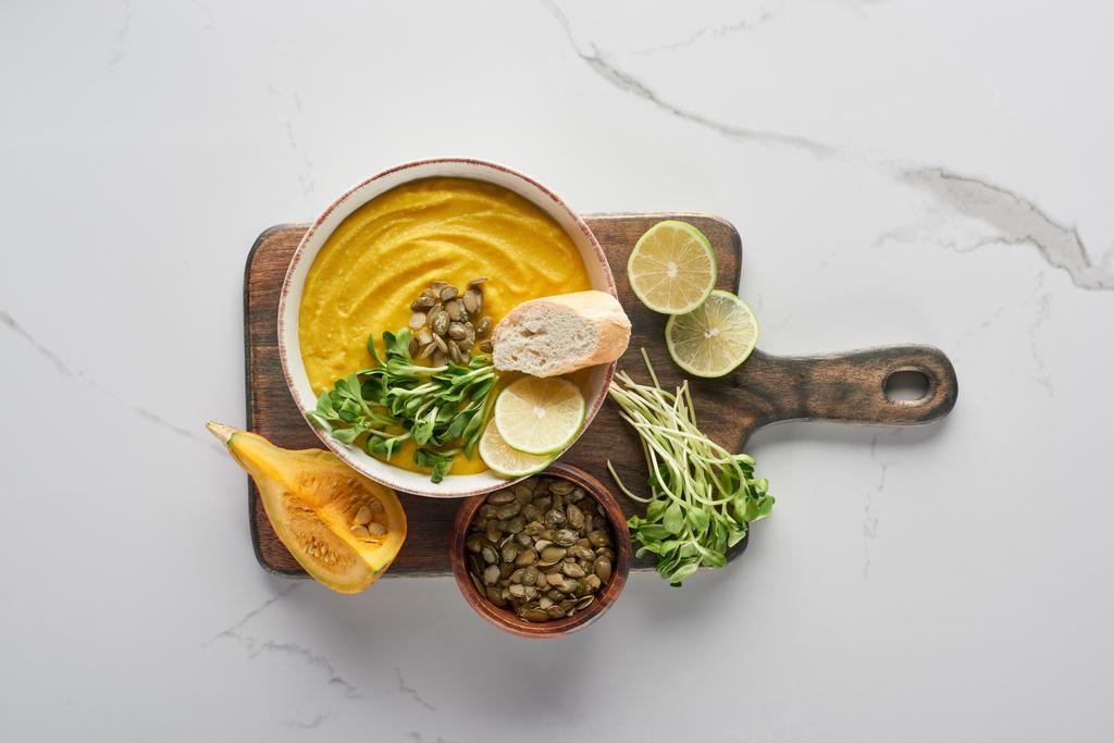 top view of delicious mashed pumpkin soup on wooden cutting board on marble surface with ingredients - 写真・画像