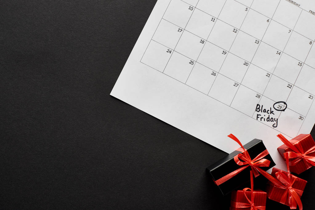 Ansicht von Geschenkboxen und Kalender mit schwarzem Freitag-Datum auf schwarzem Hintergrund - Foto, Bild
