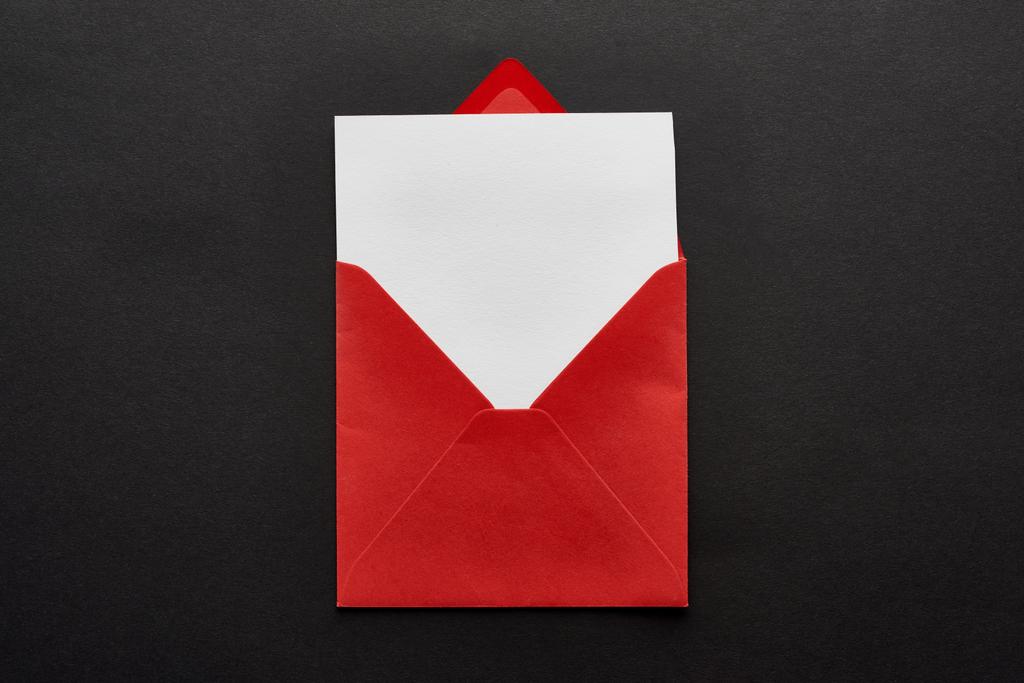 vista superior de la tarjeta en blanco en sobre rojo sobre fondo negro
 - Foto, imagen