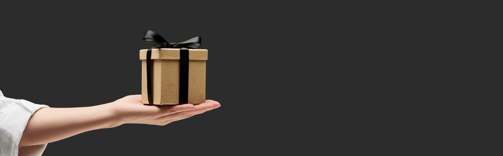 vista recortada de la mujer sosteniendo caja de regalo en la mano aislado en negro, plano panorámico
 - Foto, Imagen