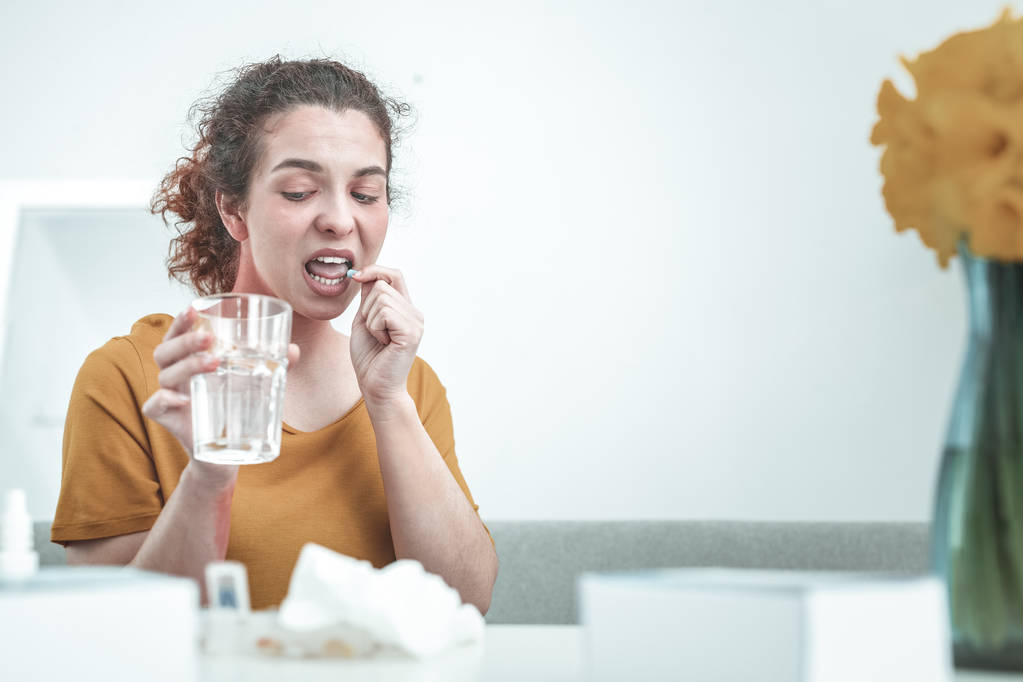 Femme tenant un verre d'eau tout en prenant des médicaments contre les allergies
 - Photo, image