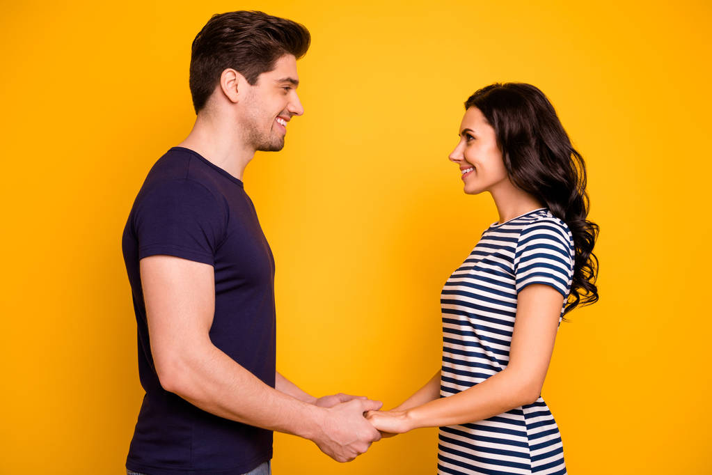 Profile side view portrait of his he her she nice attractive lovely tender affectionate cheerful cheery married spouses holding hands isolated on bright vivid shine yellow background - Photo, Image