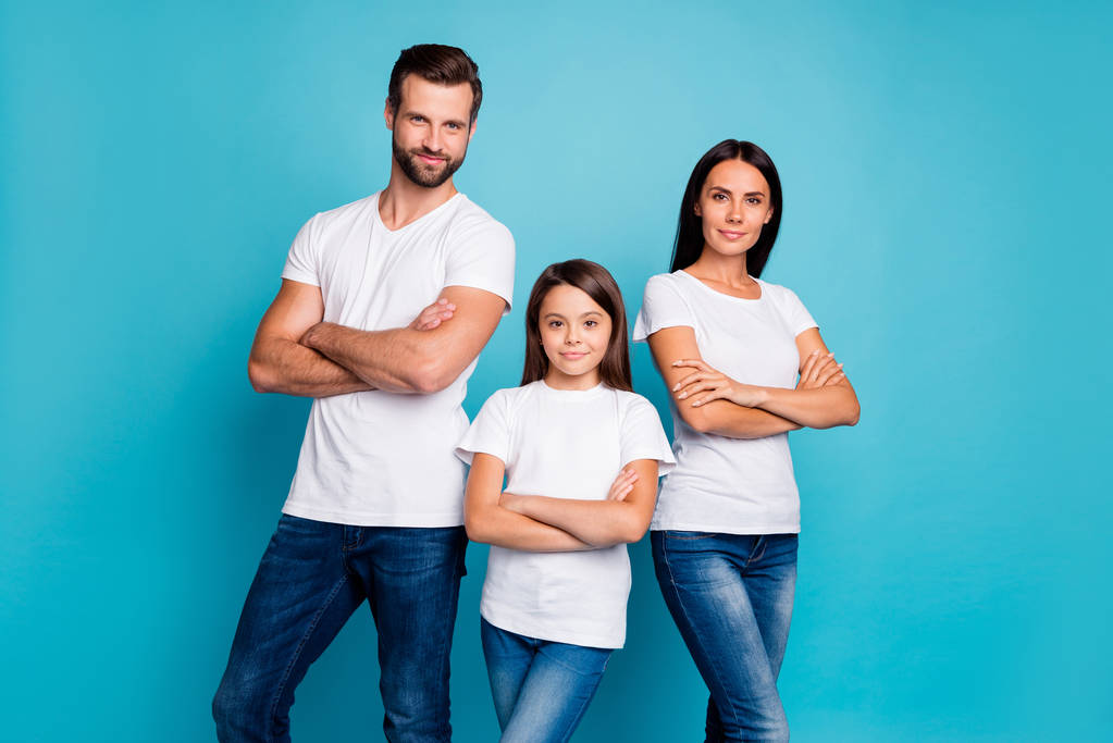 Portrait de famille focalisée avec les cheveux bruns croisant leurs mains regardant en t-shirt blanc jeans en denim isolé sur fond bleu
 - Photo, image