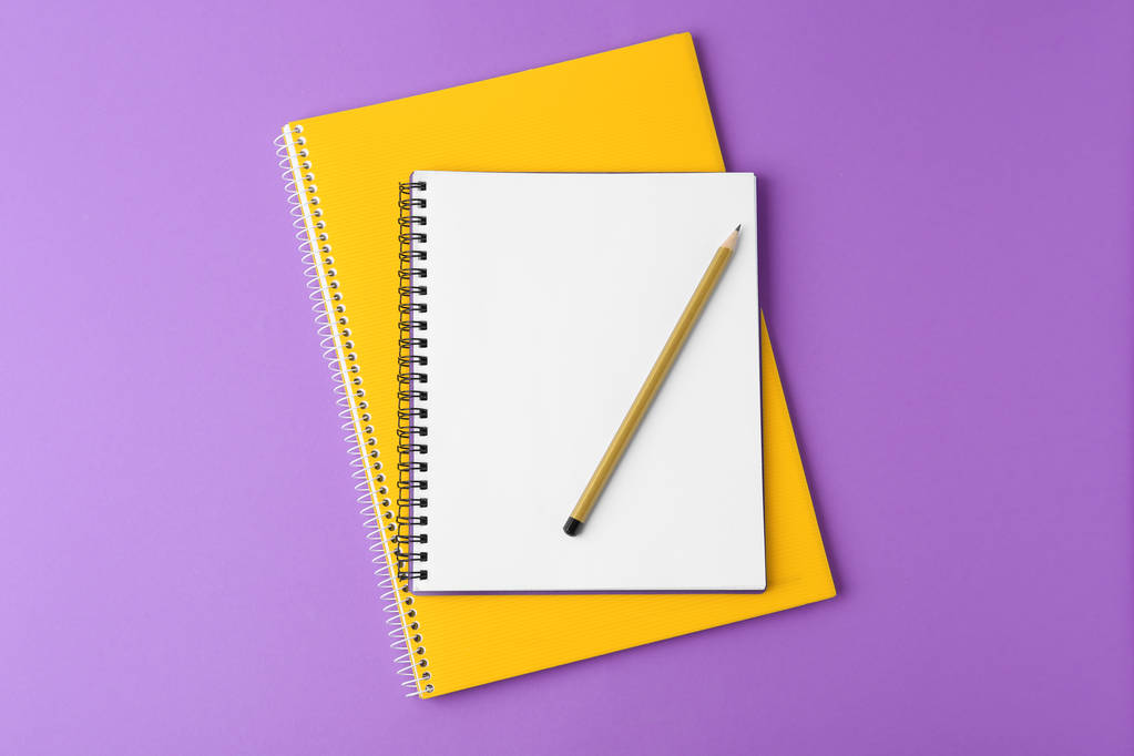 Cuadernos con lápiz sobre fondo púrpura, vista superior
 - Foto, imagen