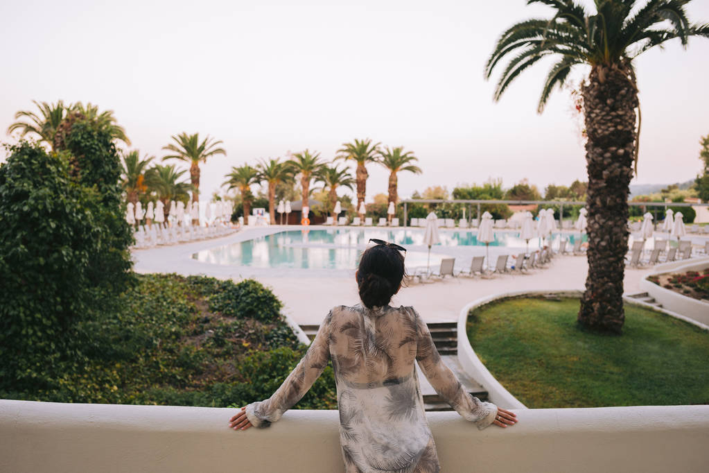 женщина стоит сзади и смотрит на тропический курорт
 - Фото, изображение