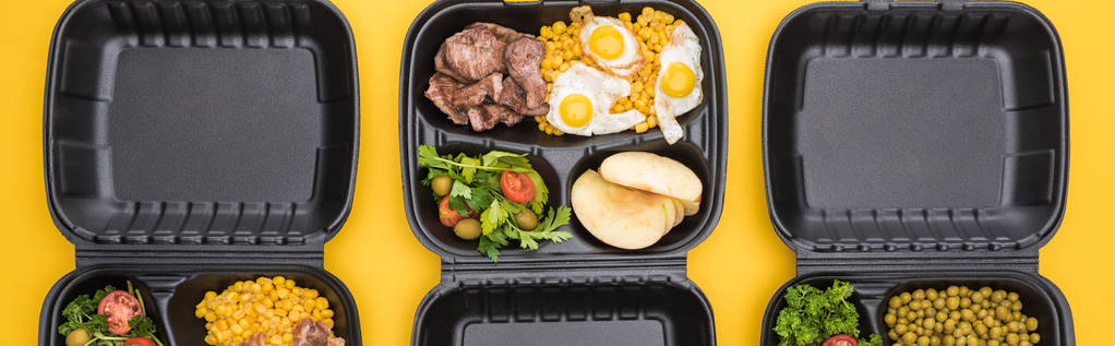panoramisch shot van eco-pakketten met groenten, appels, vlees, gebakken eieren en salades geïsoleerd op geel     - Foto, afbeelding