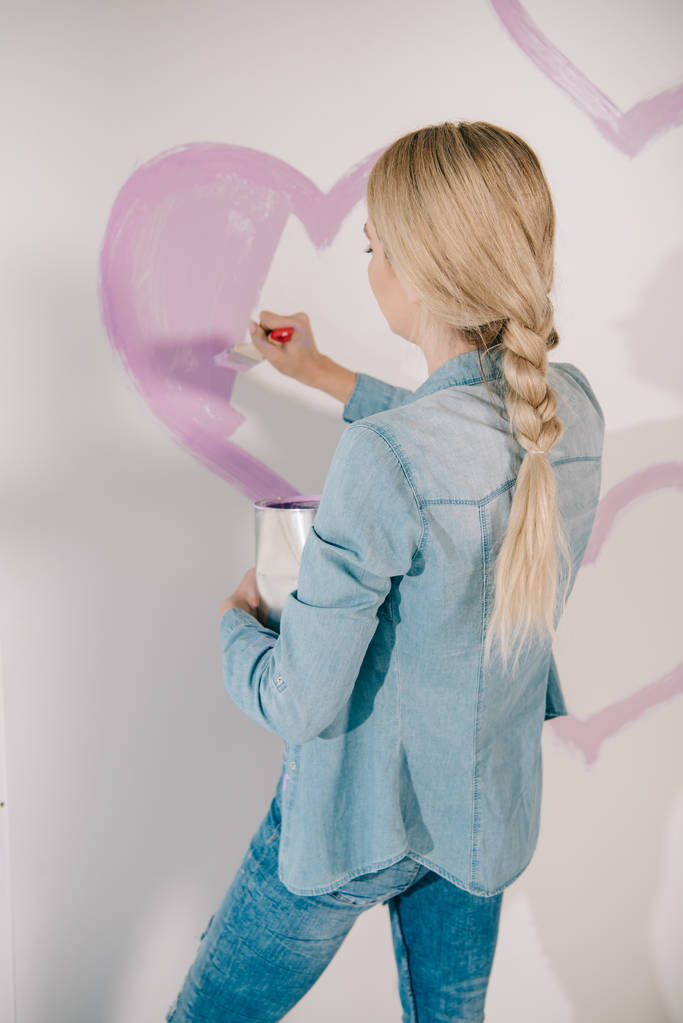 絵筆で壁にピンクのハートを描く若い女性 - 写真・画像