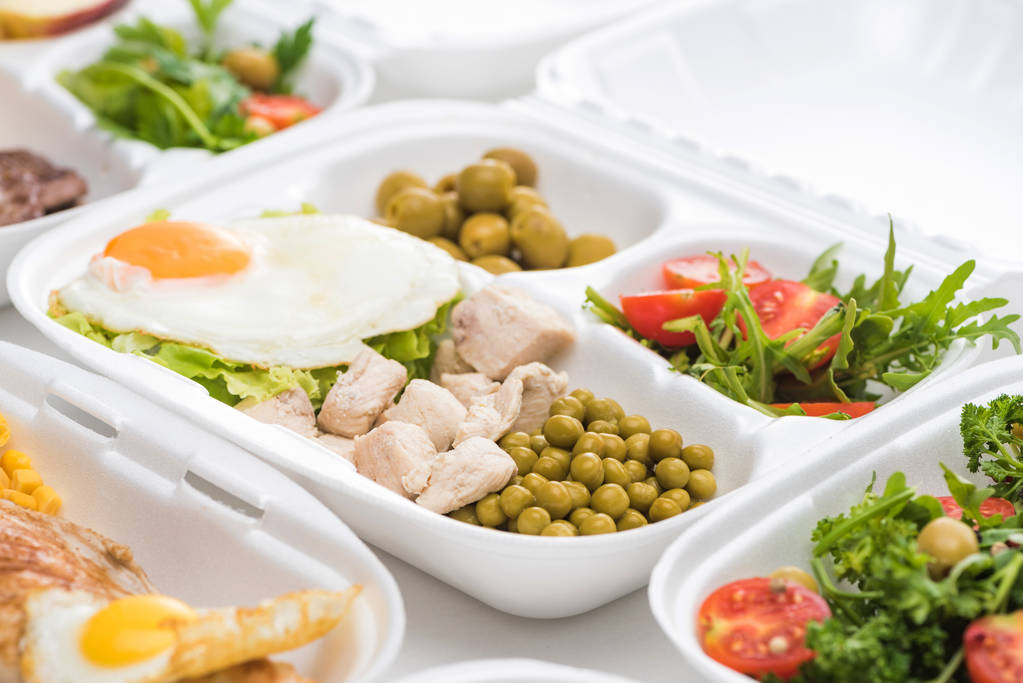 foco seletivo do pacote ecológico com legumes, carne, ovo frito e salada no fundo branco
  - Foto, Imagem