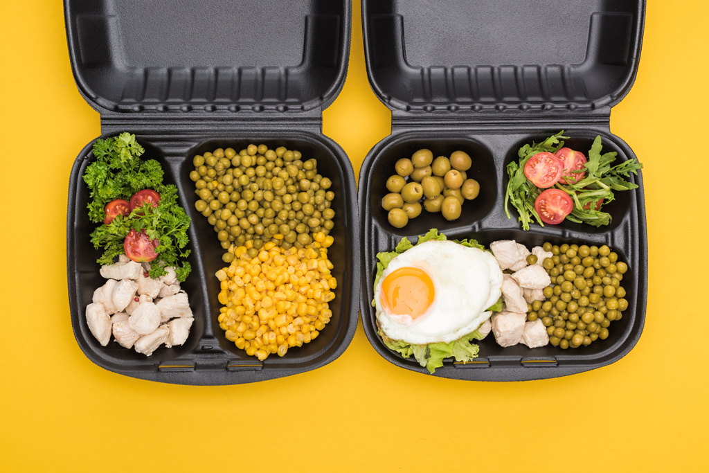 vista dall'alto di confezioni ecologiche con verdure, carne, uova fritte e insalate isolate sul giallo
  - Foto, immagini